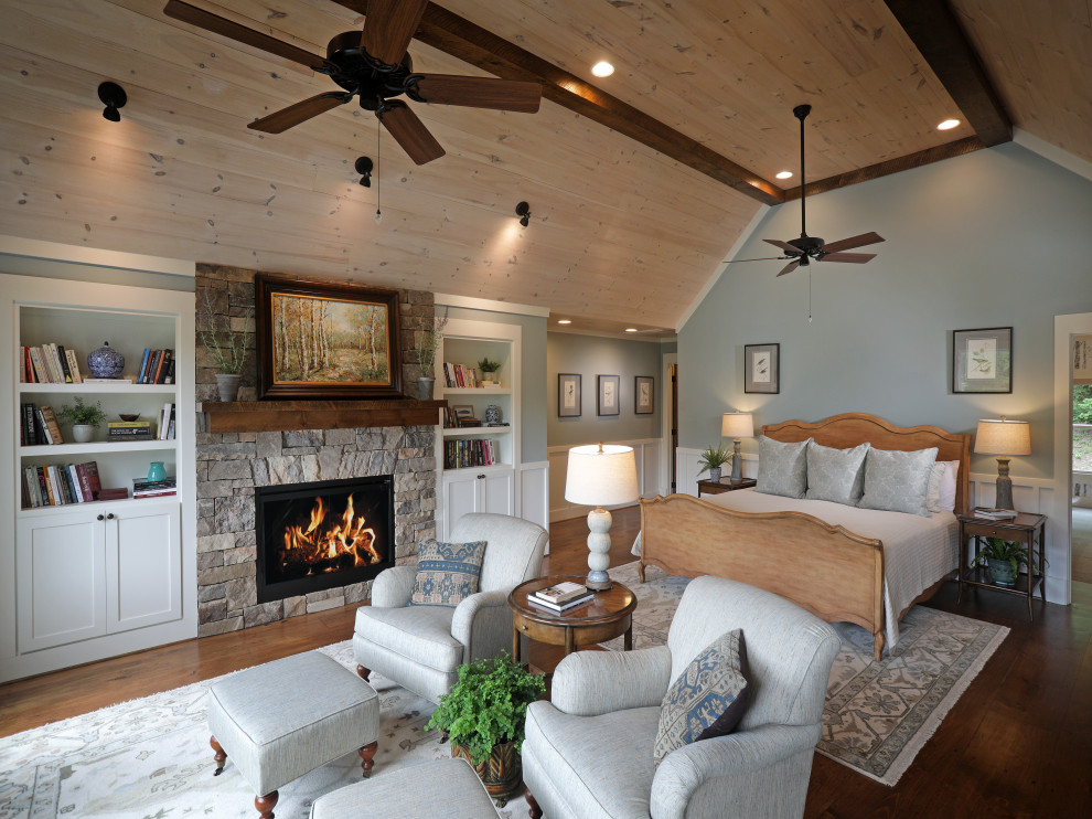 Aménagement d'une chambre montagne avec un mur bleu, parquet foncé, une cheminée standard, un manteau de cheminée en pierre de parement, un sol marron, un plafond voûté, un plafond en bois et boiseries.