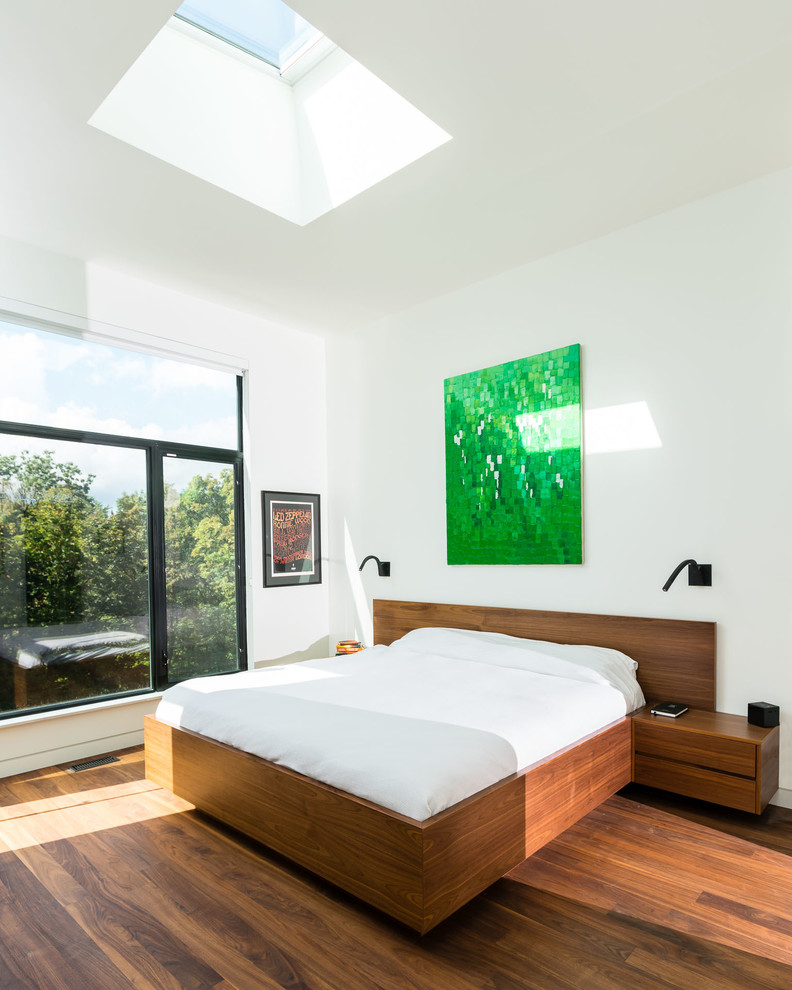 Aménagement d'une chambre moderne avec un mur blanc, un sol en bois brun et un sol marron.