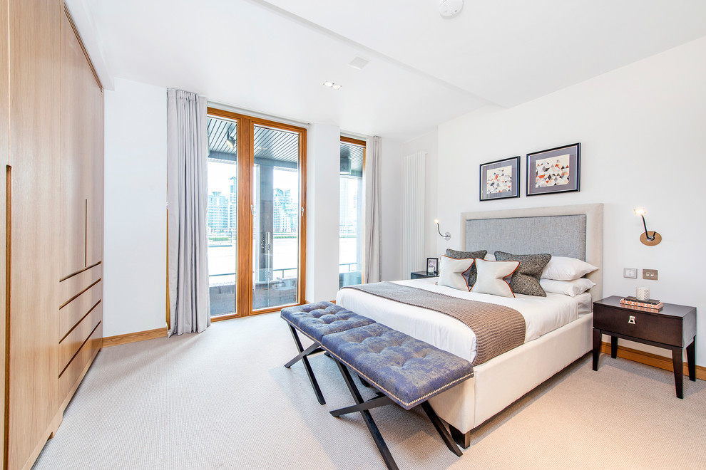 This is an example of a contemporary master bedroom in London with white walls and carpet.