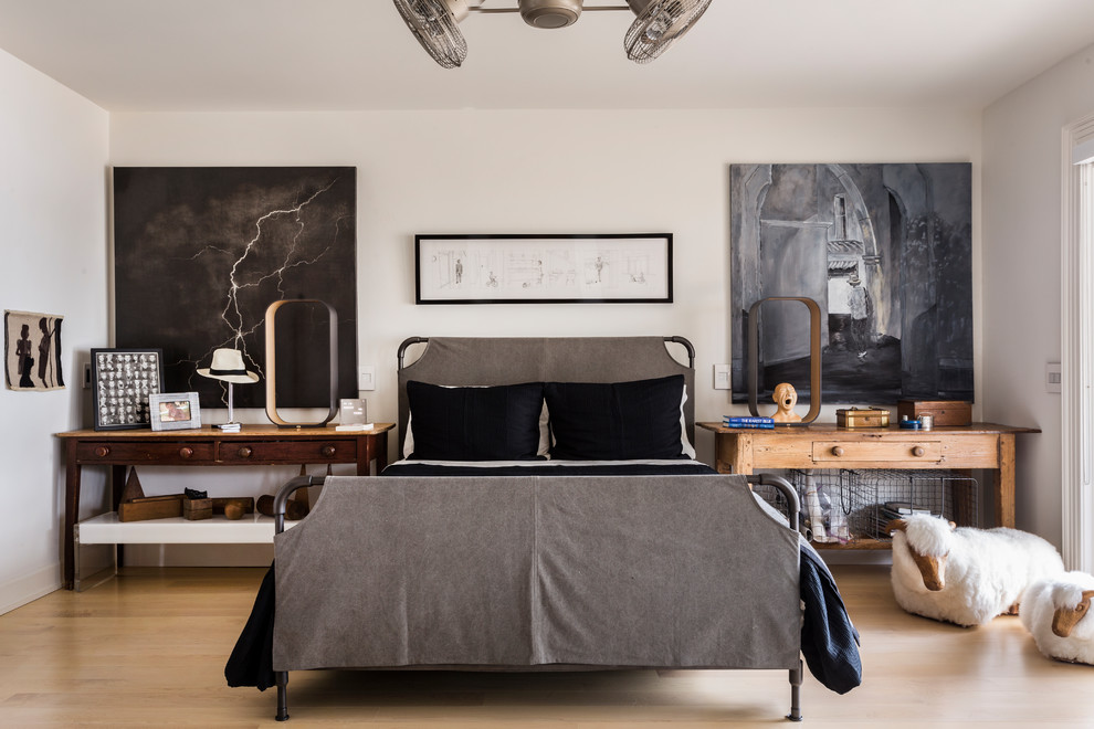 Modelo de dormitorio principal y gris y negro urbano grande sin chimenea con paredes blancas, suelo de madera clara y suelo beige