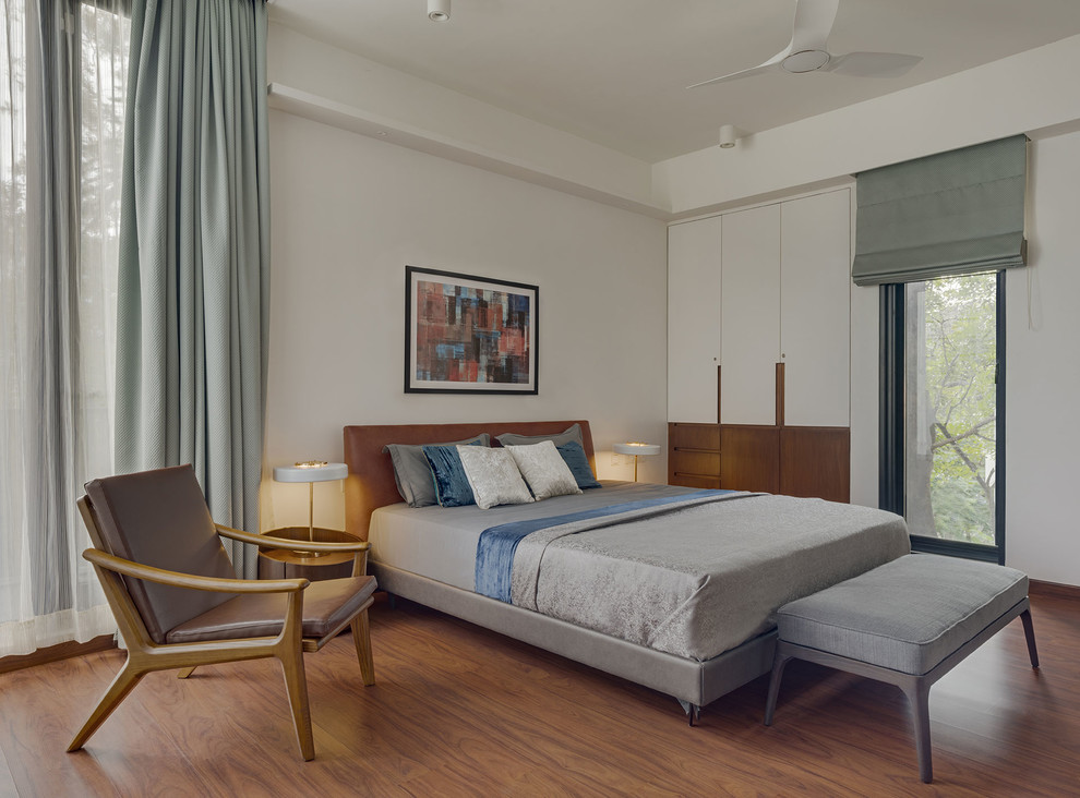 Пример оригинального дизайна: спальня в современном стиле с белыми стенами, паркетным полом среднего тона и коричневым полом