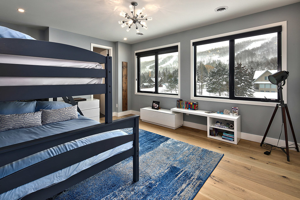 Modelo de habitación de invitados minimalista grande con paredes grises, suelo de madera en tonos medios y suelo marrón