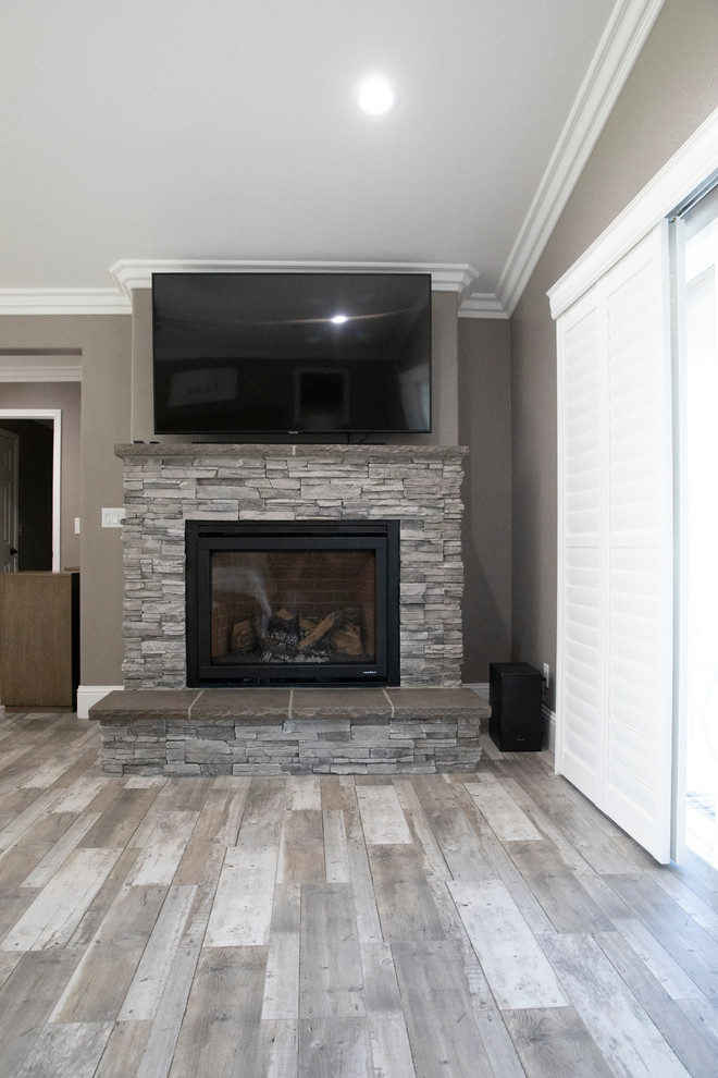 Small trendy master laminate floor and gray floor bedroom photo in Other with gray walls, a standard fireplace and a stone fireplace
