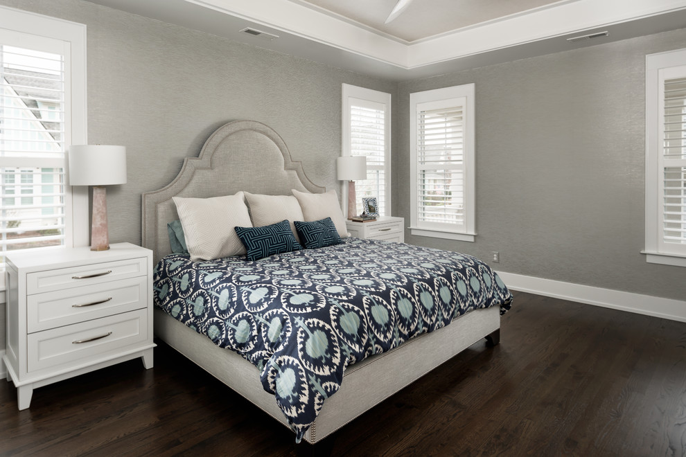 Ejemplo de dormitorio principal tradicional renovado de tamaño medio sin chimenea con suelo de madera oscura, suelo marrón, paredes grises, bandeja y papel pintado