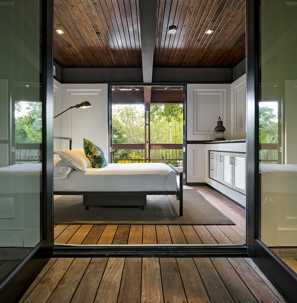 Idéer för mellanstora tropiska gästrum, med vita väggar, mellanmörkt trägolv och brunt golv