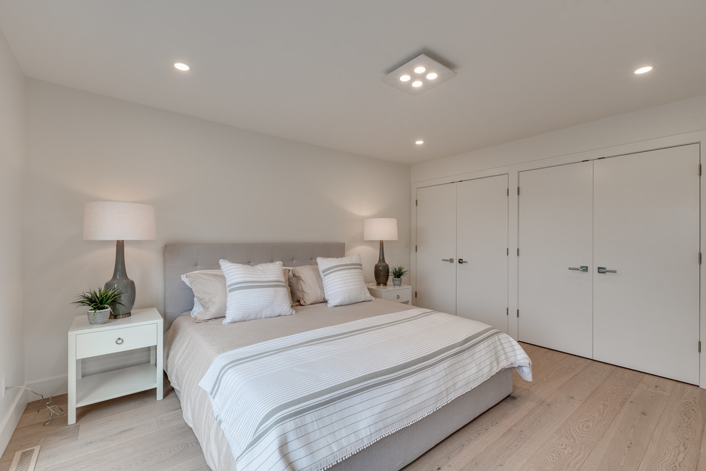 Minimalist master light wood floor bedroom photo in Vancouver with white walls