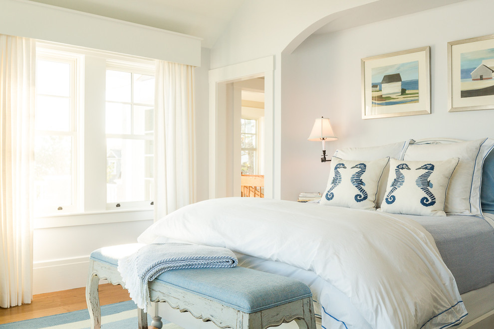 Imagen de dormitorio costero con paredes blancas y suelo de madera en tonos medios