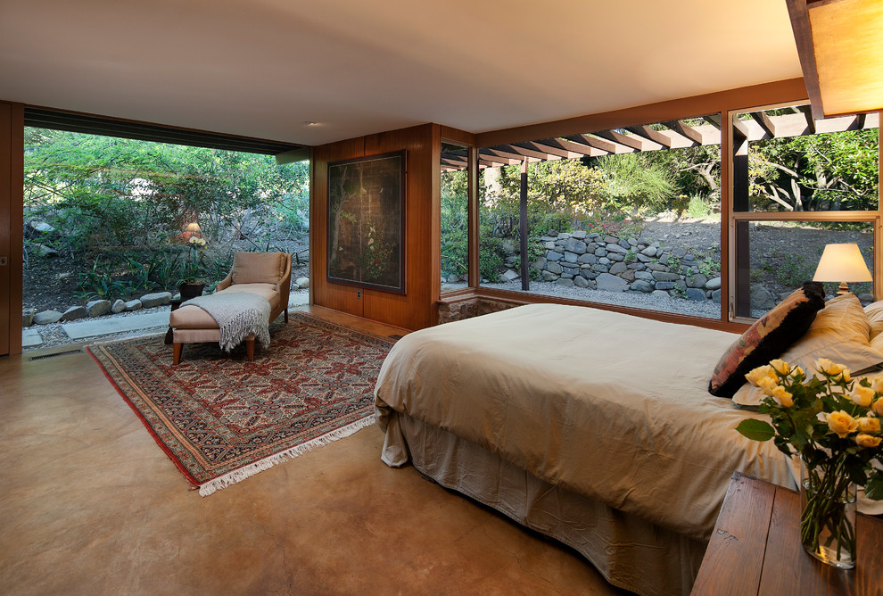На фото: хозяйская спальня среднего размера в стиле ретро с коричневыми стенами и бетонным полом с