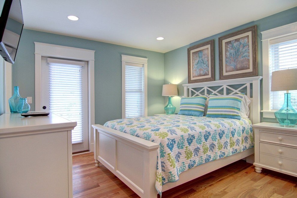 Ejemplo de habitación de invitados marinera de tamaño medio sin chimenea con paredes azules y suelo de madera en tonos medios