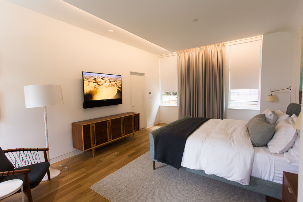 На фото: хозяйская спальня среднего размера в современном стиле с белыми стенами, светлым паркетным полом и коричневым полом без камина