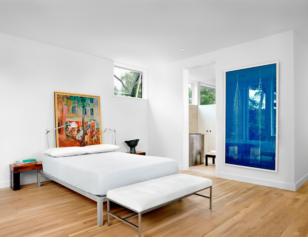 Cette image montre une chambre parentale minimaliste avec un mur blanc et parquet clair.