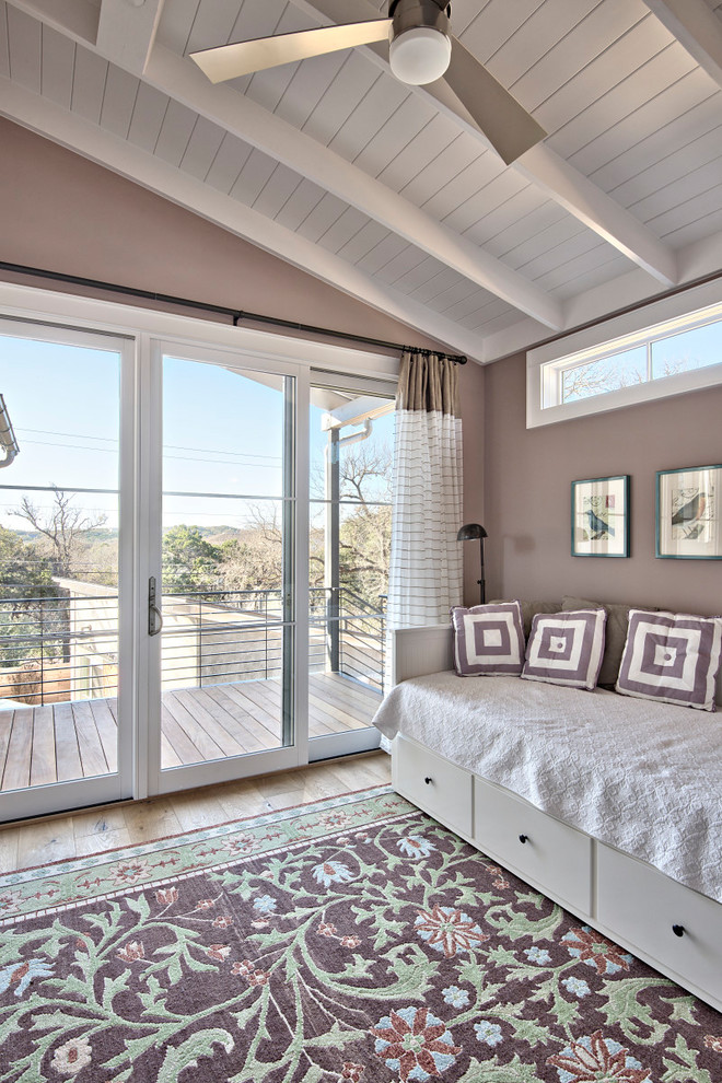 Large classic guest bedroom in Austin with pink walls, light hardwood flooring, brown floors and no fireplace.