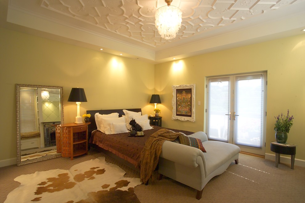 Стильный дизайн: большая хозяйская спальня в современном стиле с желтыми стенами, ковровым покрытием, бежевым полом, стандартным камином и фасадом камина из металла - последний тренд