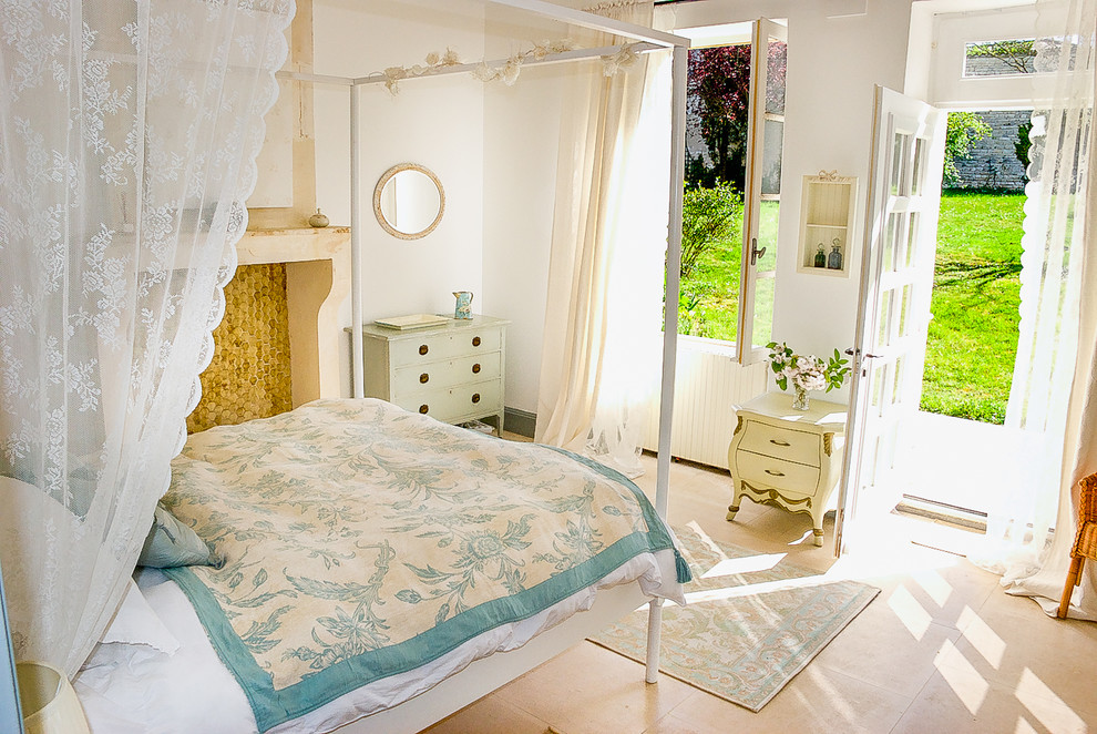 Стильный дизайн: гостевая спальня среднего размера, (комната для гостей) в стиле кантри с белыми стенами, полом из травертина, стандартным камином, фасадом камина из камня и бежевым полом - последний тренд