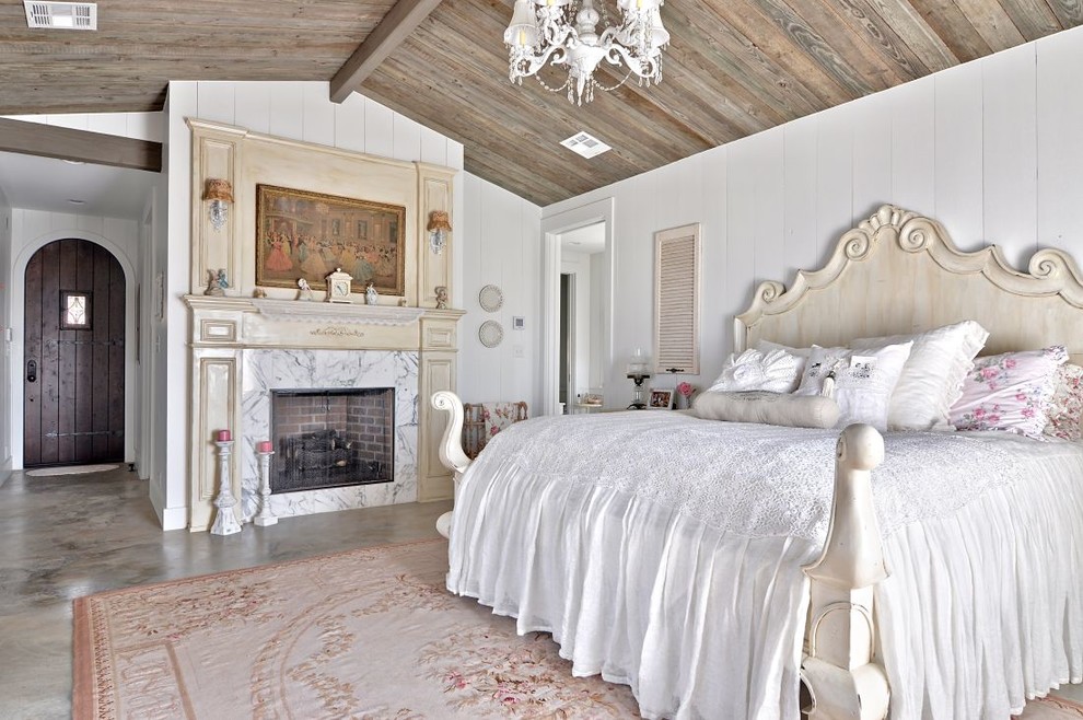 Shabby-Chic Schlafzimmer mit weißer Wandfarbe, Betonboden, Kamin und Kaminumrandung aus Stein in Austin