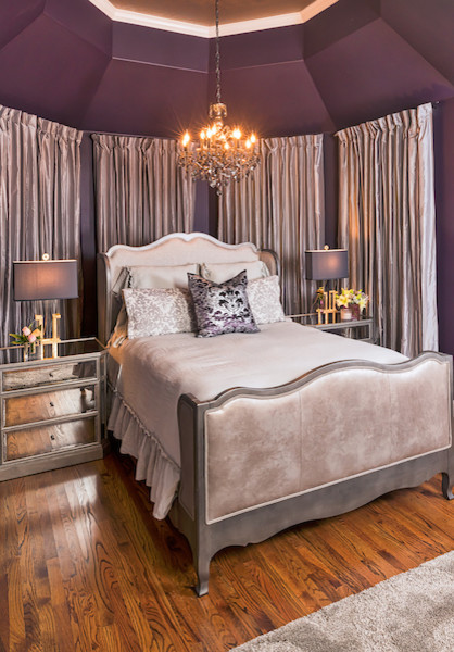Modelo de dormitorio principal tradicional con paredes púrpuras y suelo de madera clara