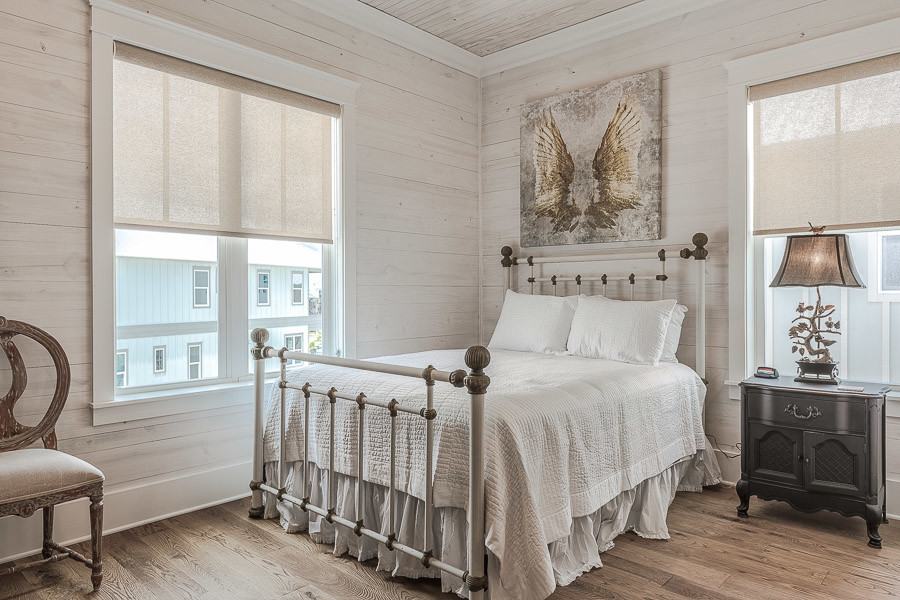 Diseño de habitación de invitados costera grande sin chimenea con paredes beige y suelo de madera en tonos medios
