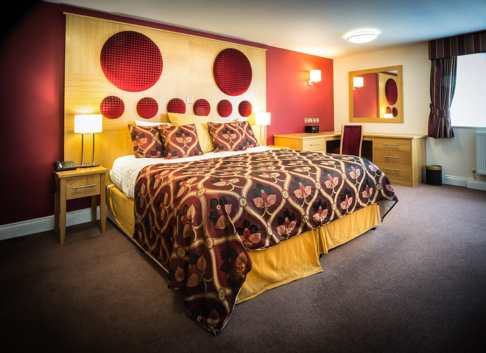 Large traditional guest bedroom in Other with red walls and carpet.