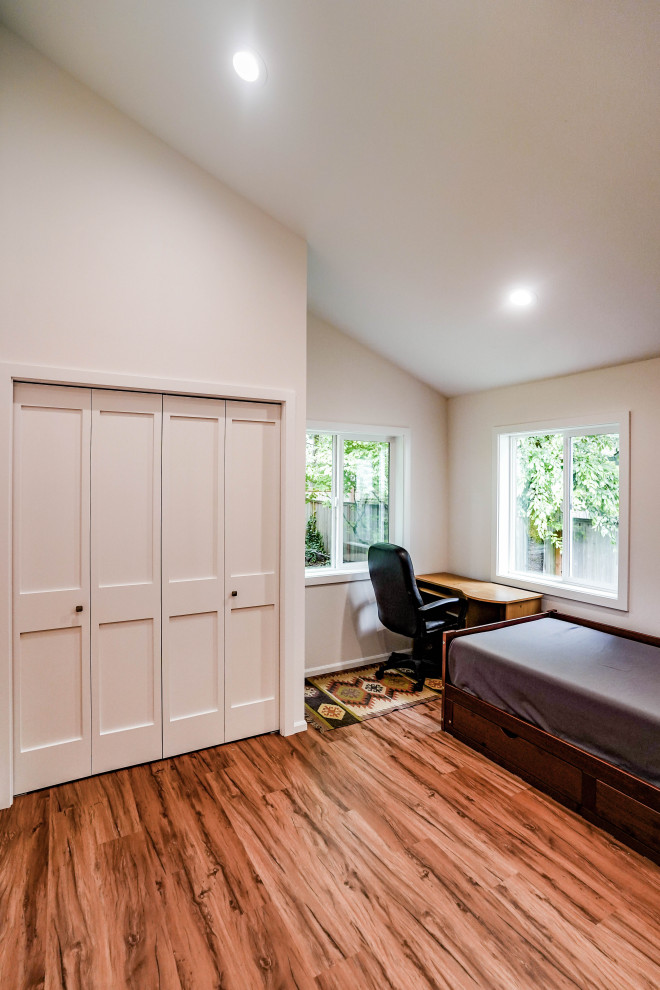 Modelo de habitación de invitados abovedada tradicional renovada de tamaño medio con paredes blancas, suelo vinílico y suelo marrón