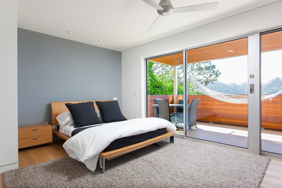 Diseño de dormitorio moderno sin chimenea con paredes grises y suelo de madera clara