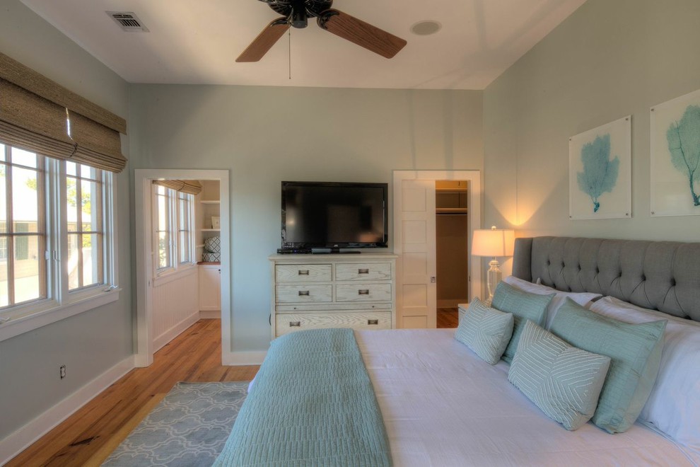 Modelo de dormitorio principal costero de tamaño medio con paredes verdes y suelo de madera en tonos medios