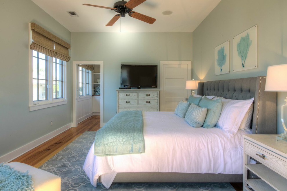 Ejemplo de dormitorio principal marinero de tamaño medio sin chimenea con paredes verdes y suelo de madera en tonos medios