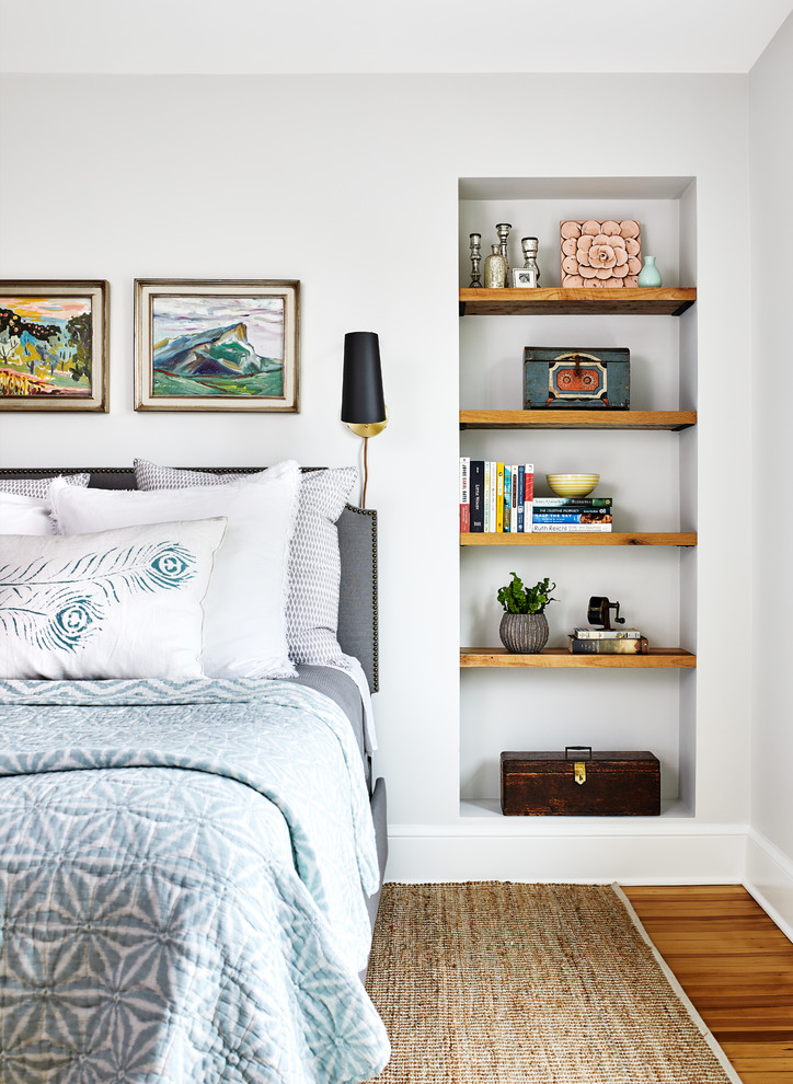Diseño de dormitorio costero con paredes blancas, suelo de madera en tonos medios y suelo marrón