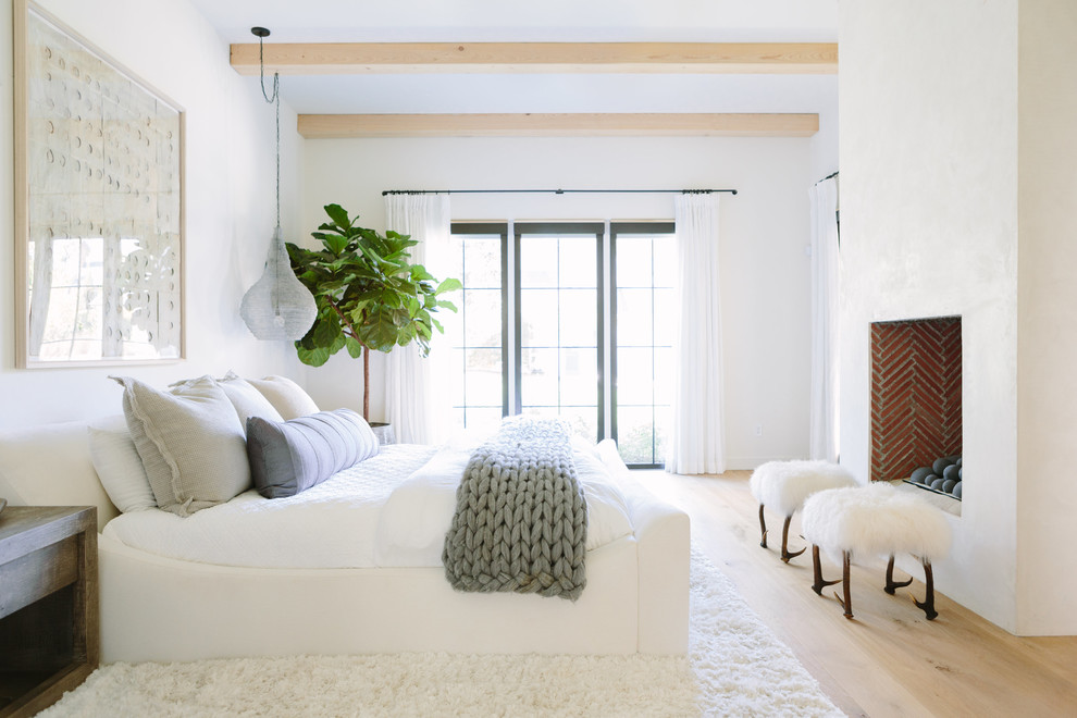 ナッシュビルにあるビーチスタイルのおしゃれな主寝室 (白い壁、淡色無垢フローリング、標準型暖炉、ベージュの床、グレーとクリーム色) のインテリア