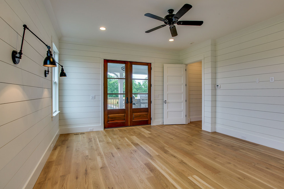 Mid-sized cottage guest light wood floor bedroom photo in Nashville with white walls