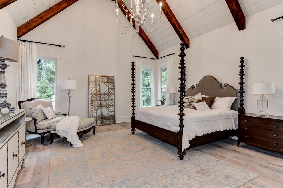 Imagen de dormitorio principal tradicional grande sin chimenea con paredes blancas y suelo de madera clara