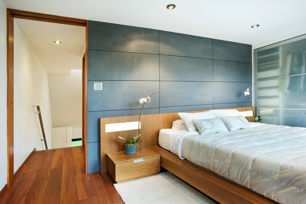 На фото: спальня в современном стиле с паркетным полом среднего тона