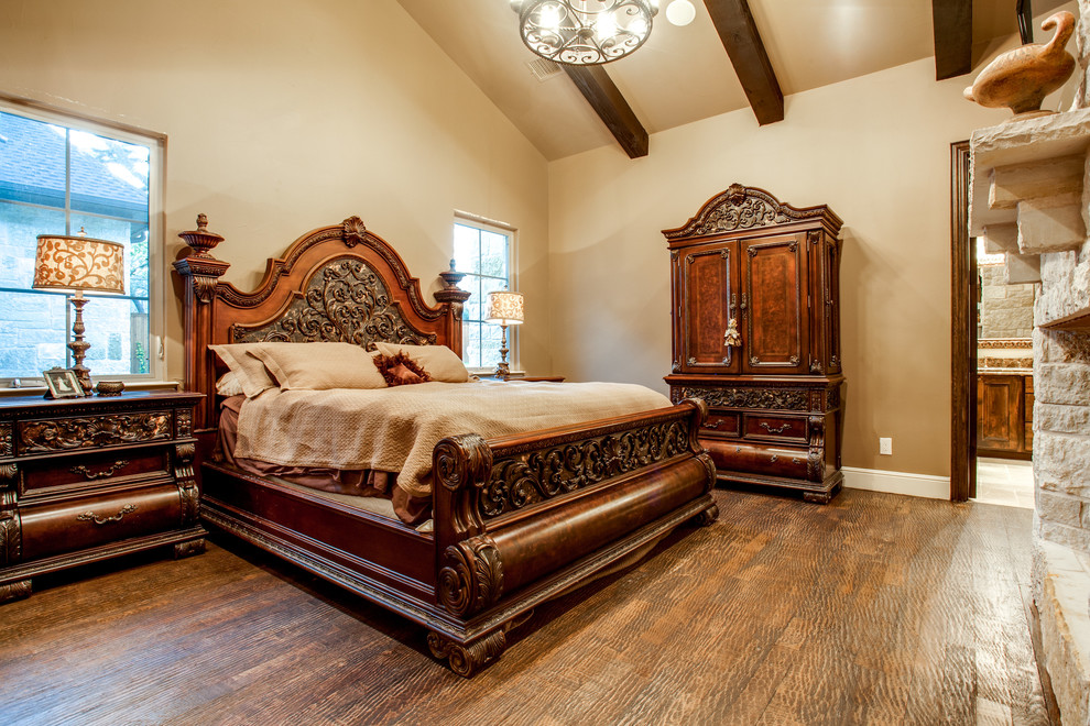 Diseño de dormitorio principal clásico grande con paredes blancas, suelo de madera en tonos medios, todas las chimeneas y marco de chimenea de piedra