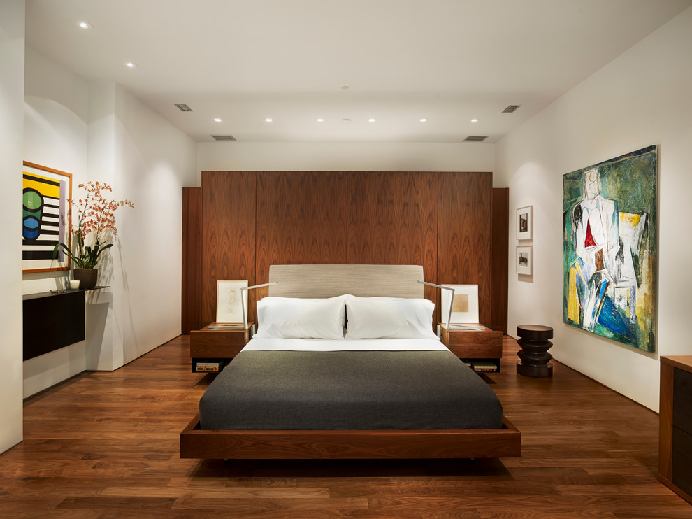 На фото: спальня в современном стиле с белыми стенами и темным паркетным полом без камина с
