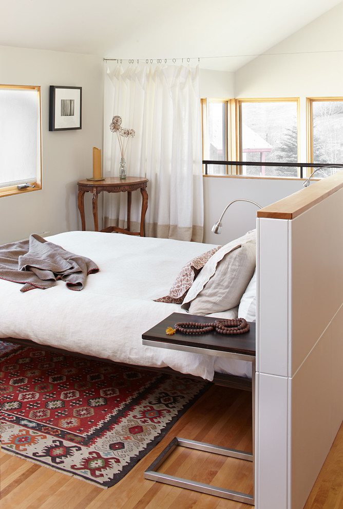 Diseño de dormitorio tipo loft contemporáneo pequeño con paredes grises y suelo de madera clara
