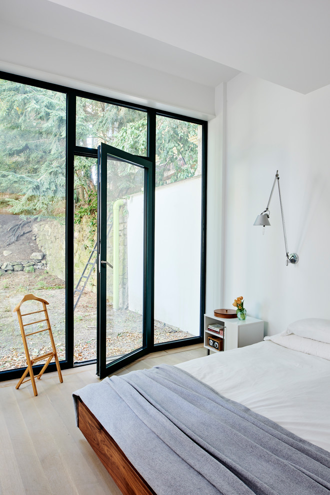 Imagen de dormitorio principal industrial con paredes blancas y suelo de madera clara