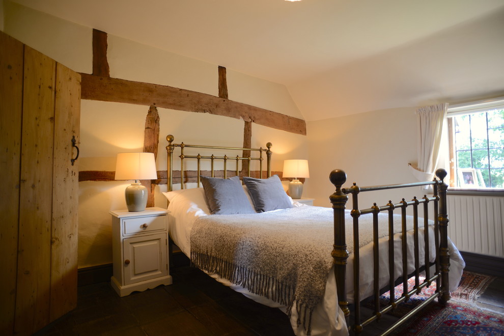 Photo of a medium sized rural guest bedroom in Sussex with white walls, dark hardwood flooring, a corner fireplace, a plastered fireplace surround and brown floors.