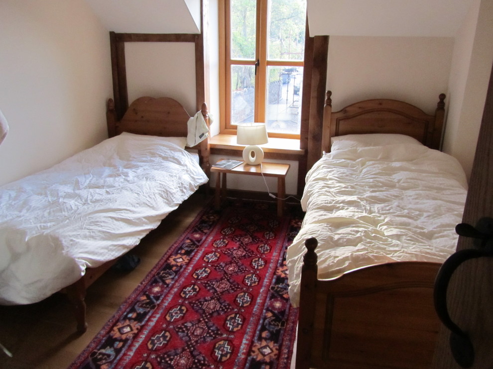 Ispirazione per una camera degli ospiti country di medie dimensioni con pareti beige, pavimento in legno massello medio e nessun camino