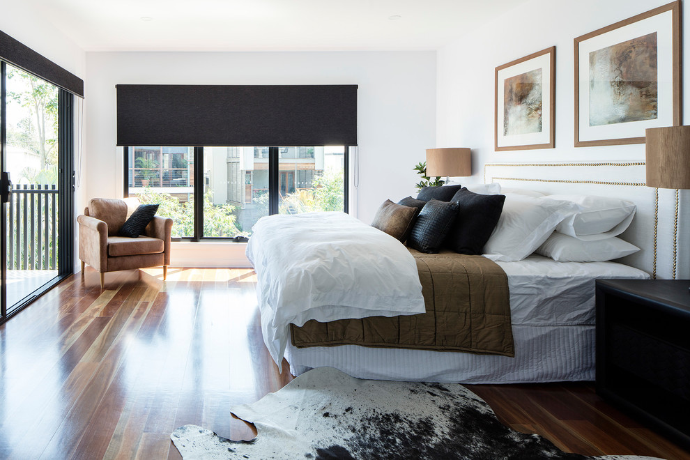 Ejemplo de dormitorio principal actual de tamaño medio con paredes blancas, suelo de madera en tonos medios y suelo marrón