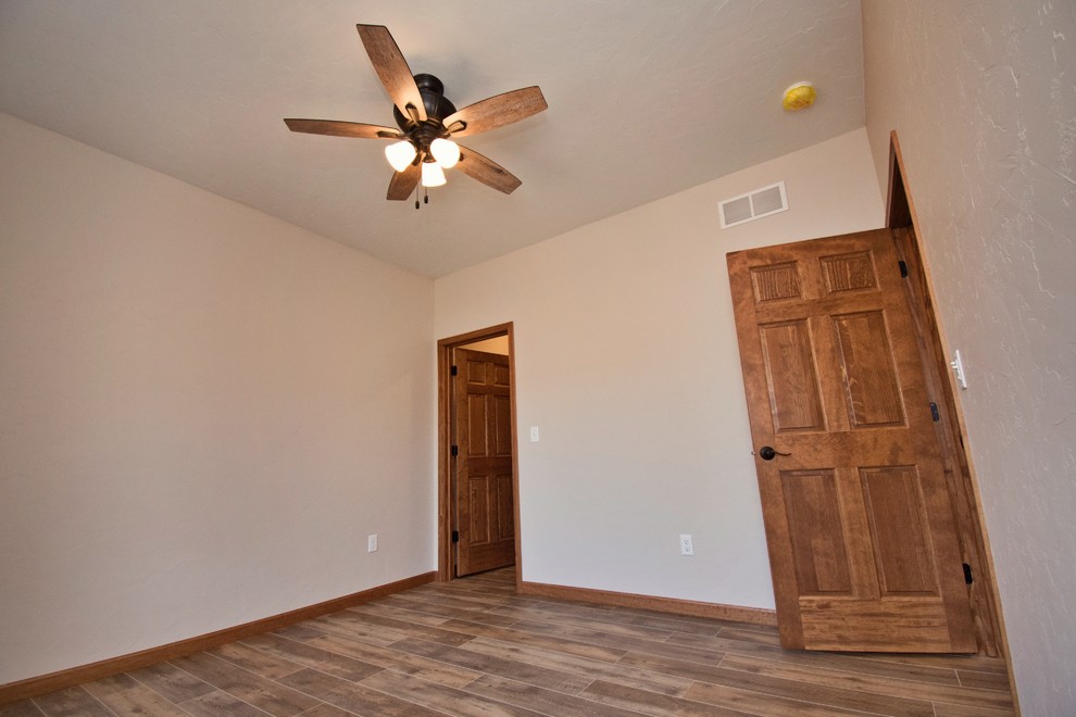 Small farmhouse guest medium tone wood floor and brown floor bedroom photo in Other with white walls