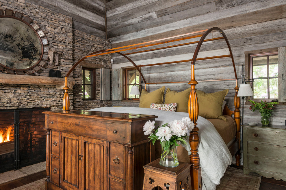 Rustic master bedroom in Other with a standard fireplace and a stone fireplace surround.