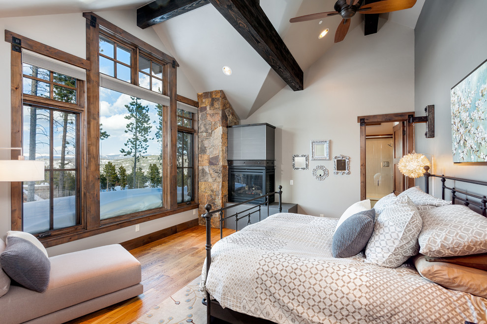 Design ideas for a rustic bedroom in Denver with grey walls, medium hardwood flooring and a corner fireplace.