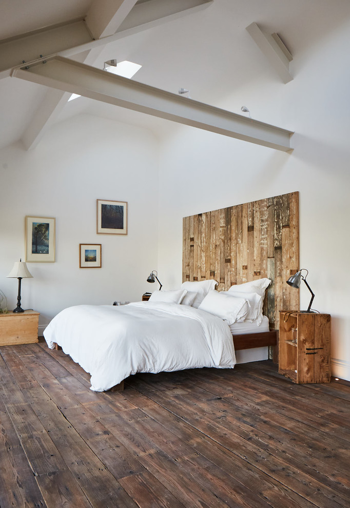 Imagen de dormitorio principal y blanco y madera rural grande sin chimenea con paredes blancas, suelo de madera oscura y suelo marrón