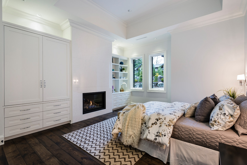 Design ideas for an expansive rustic guest bedroom in Vancouver with grey walls, medium hardwood flooring, a standard fireplace, a stone fireplace surround and brown floors.