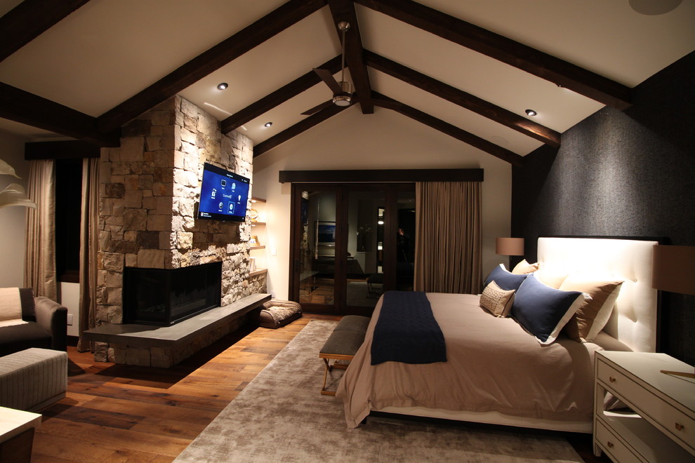 Großes Modernes Hauptschlafzimmer mit schwarzer Wandfarbe, braunem Holzboden, Eckkamin und Kaminumrandung aus Stein in Phoenix