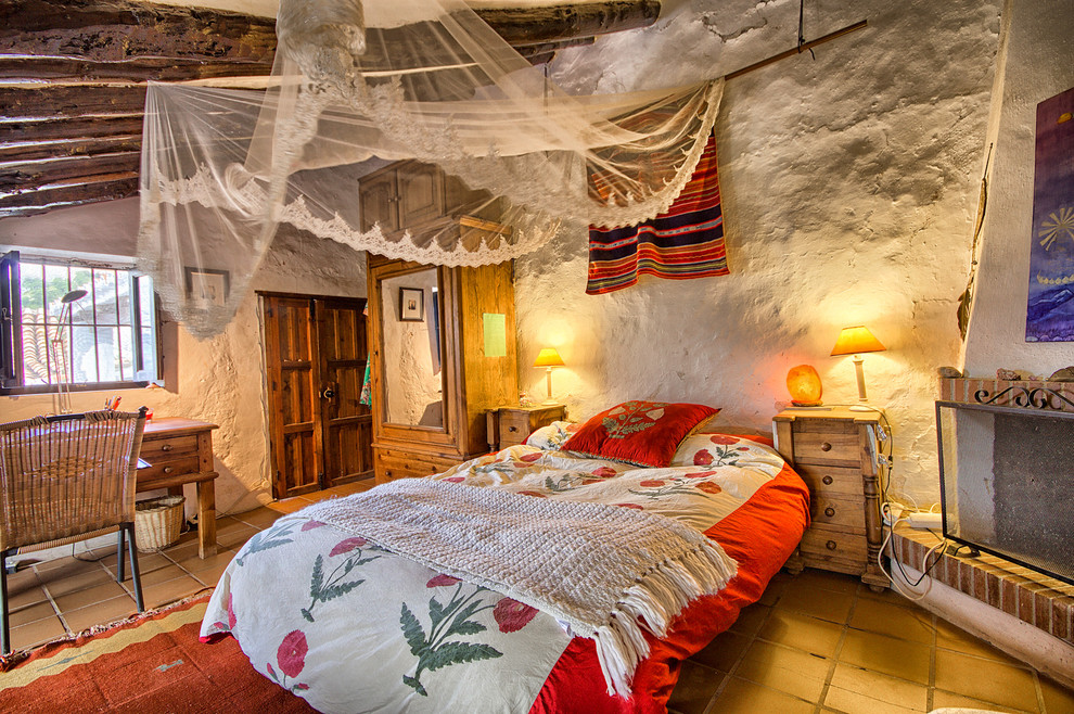 Foto på ett lantligt sovrum, med en öppen hörnspis och klinkergolv i terrakotta