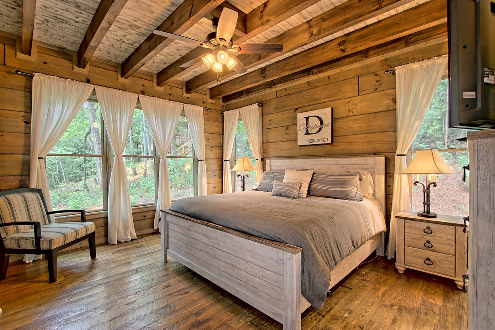 Kleines Rustikales Hauptschlafzimmer mit braunem Boden, brauner Wandfarbe und dunklem Holzboden in Sonstige