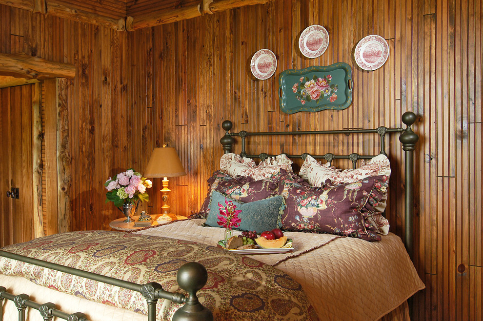 Cette image montre une grande chambre d'amis chalet avec un mur beige, un sol en bois brun et aucune cheminée.