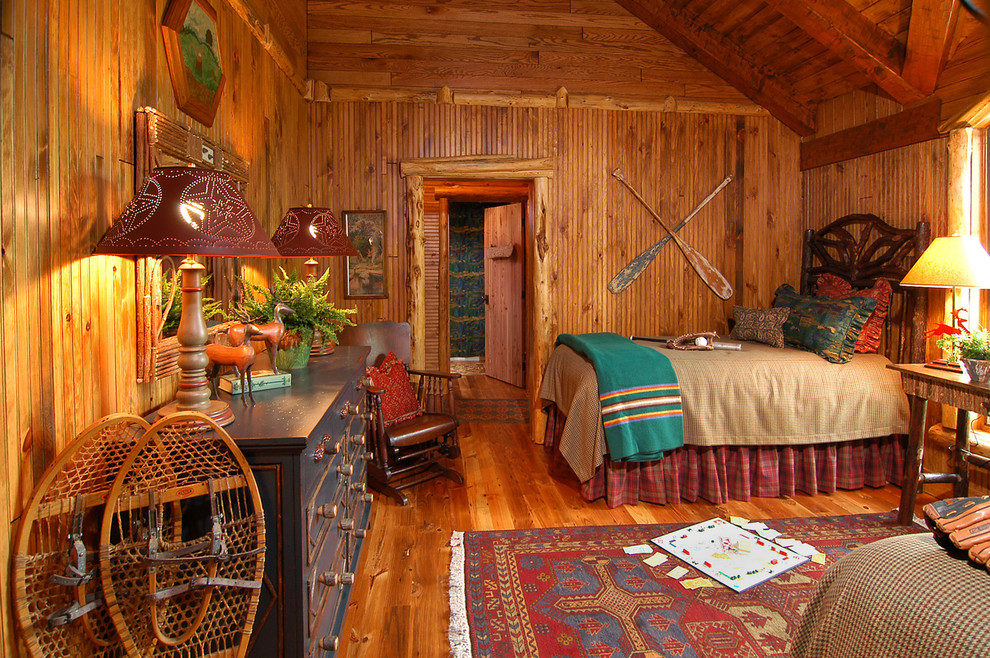 Cette image montre une grande chambre d'amis chalet avec un mur beige, un sol en bois brun et aucune cheminée.