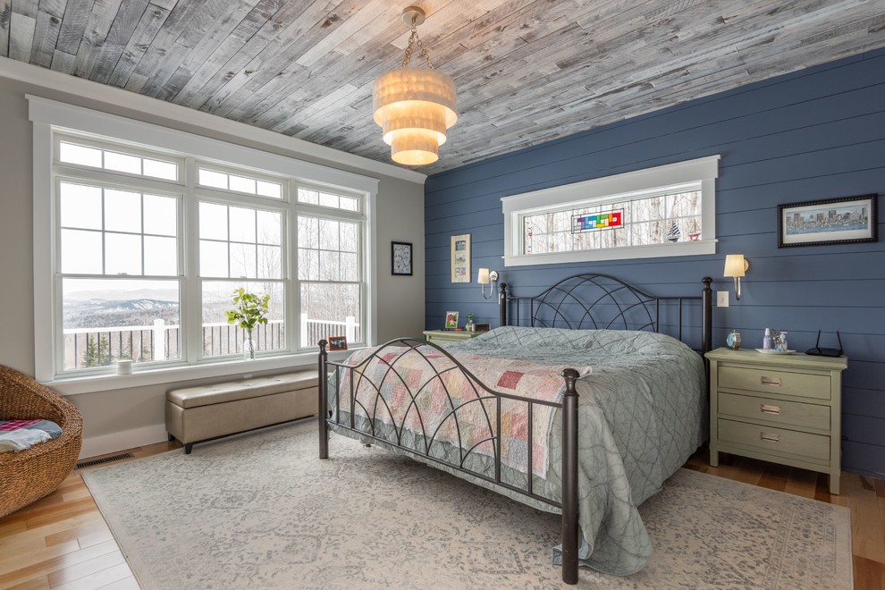 Diseño de dormitorio campestre sin chimenea con paredes azules y suelo de madera clara