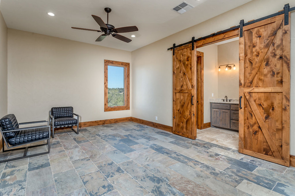 Ejemplo de habitación de invitados rural grande con paredes beige, suelo de pizarra y suelo gris